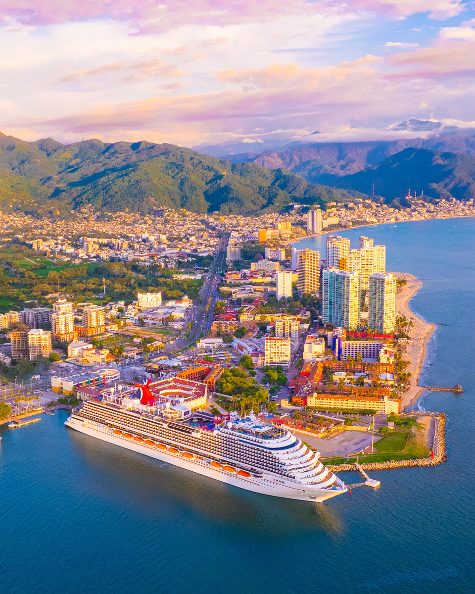 Cruise ship docked in the port of Puerto Vallarta at sunset, with the city and mountains in the background