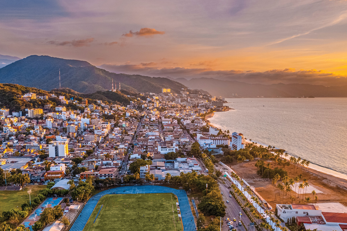 Aerial view of Puerto Vallarta at sunset, with the coastline, the mountains and the boardwalk